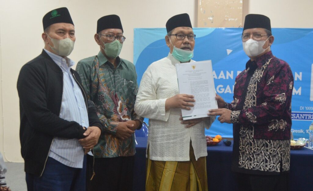 Direktur PTKI Kementerian Agama Republik Indonesia, Suyitno menyerahkan SK penyatuan kepada Pemangku Pondok Pesantren Qomaruddin, KH. Iklil Sholeh di Aula Universitas Qomaruddin, pada Jumat 10 Juni 2022. Foto: QOM.
